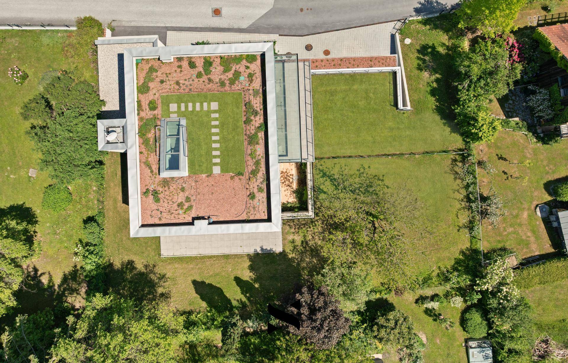 Vogelperspektive eines modernen Hauses mit Gründach und weitläufigem Gartenbereich.