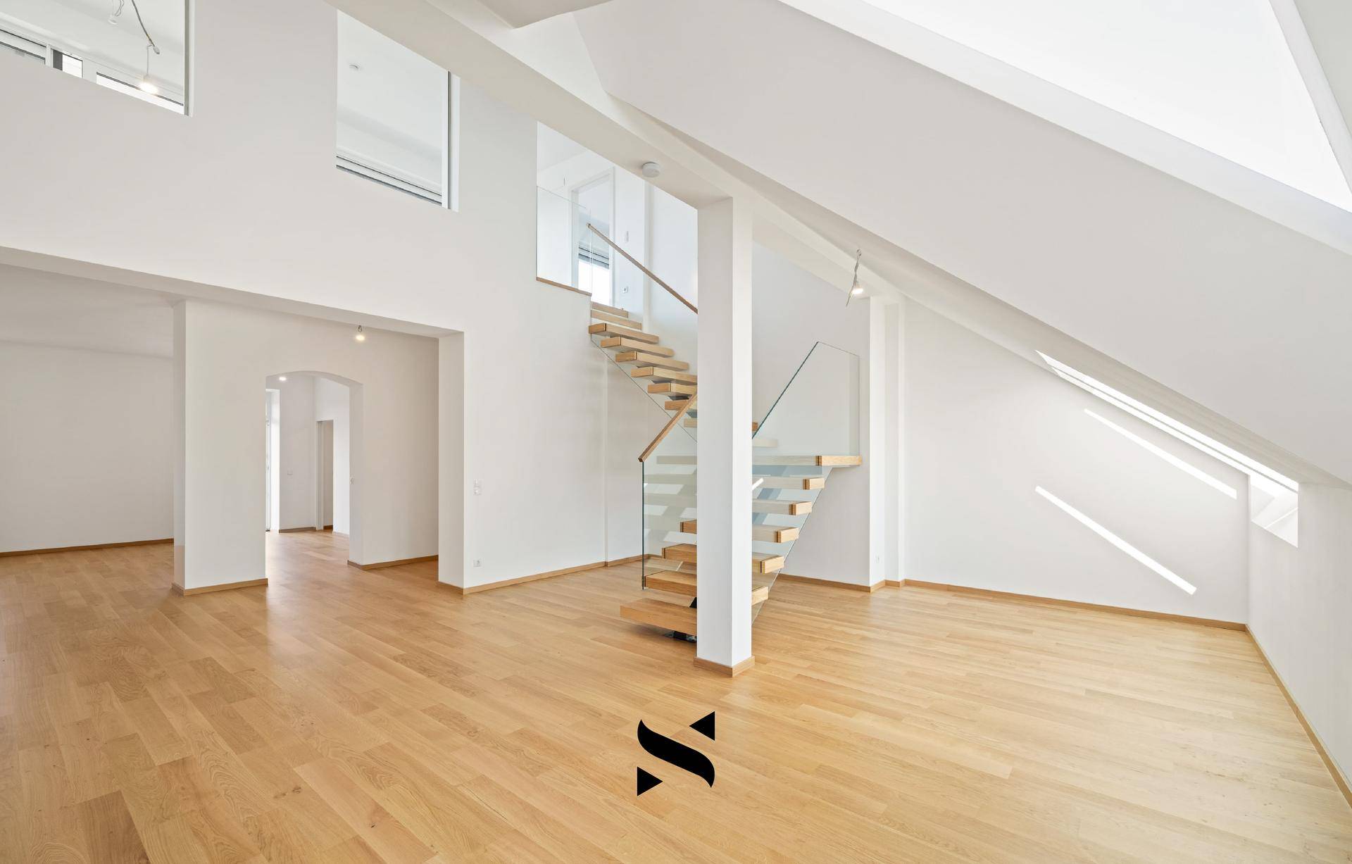 Heller, offener Wohnbereich mit Holzparkett, moderner Treppe und Dachschrägenfenstern.