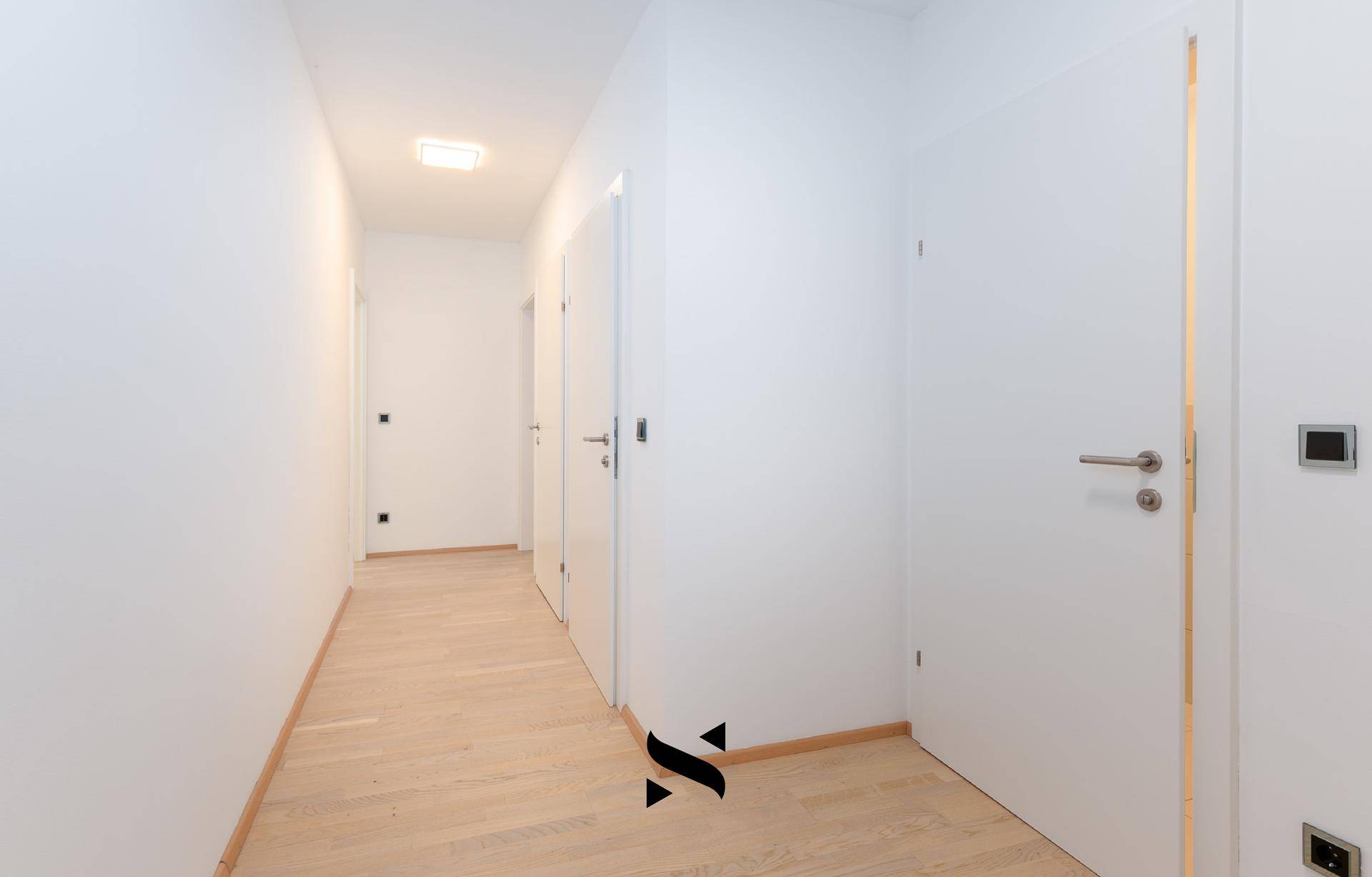 Heller Flur mit Parkettboden und mehreren Türen, der verschiedene Räume miteinander verbindet.