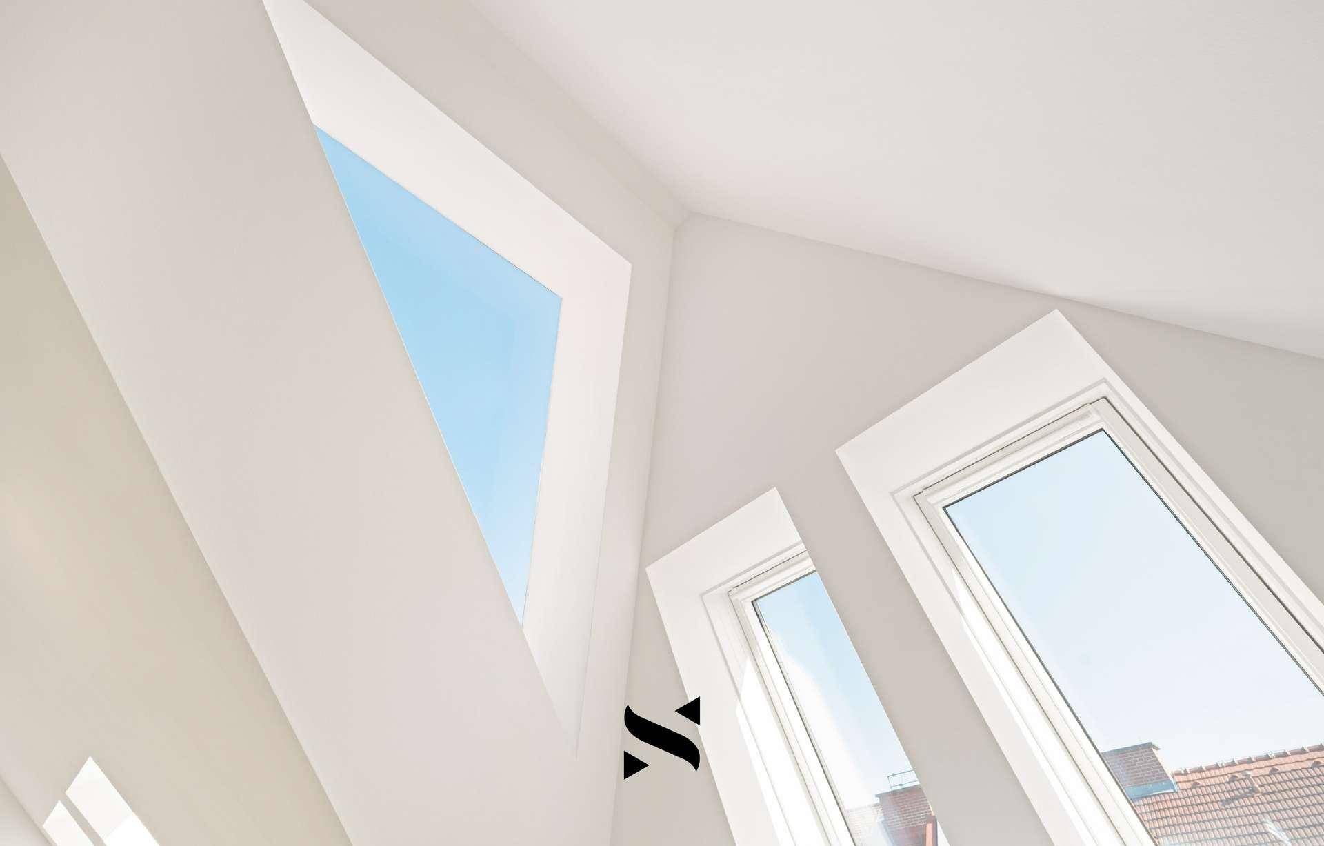 Detailaufnahme von modernen Dachfenstern, die den Raum mit Tageslicht versorgen.
