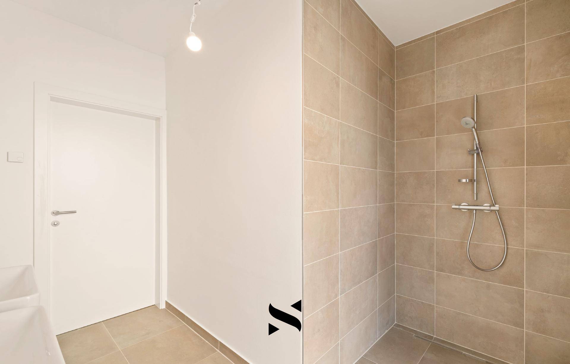 Geräumige Dusche mit beigefarbenen Fliesen und moderner Armatur im Badezimmer.