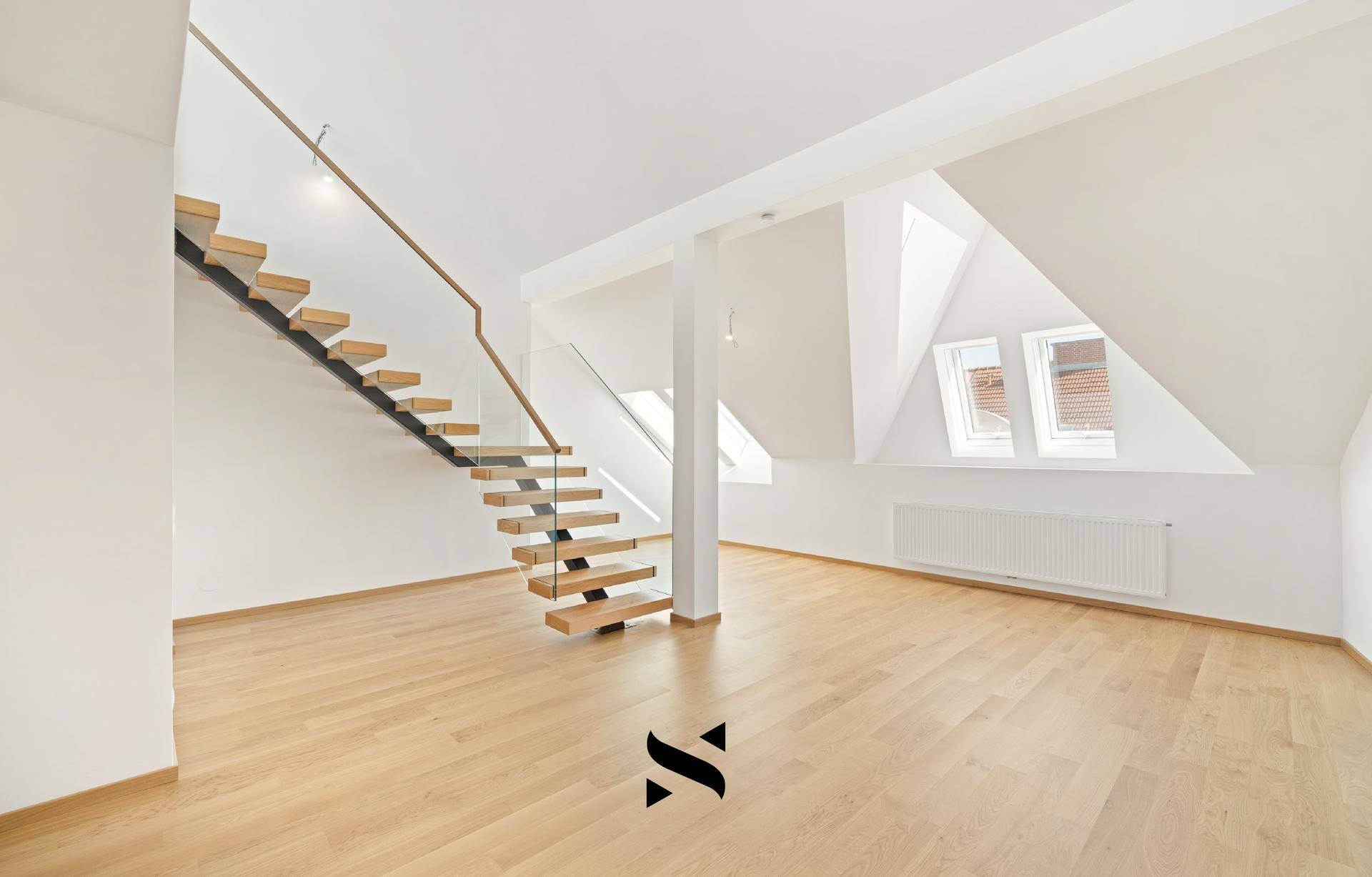 Geräumiger Wohnbereich mit Parkettboden, moderner Treppe und großen Dachfenstern.