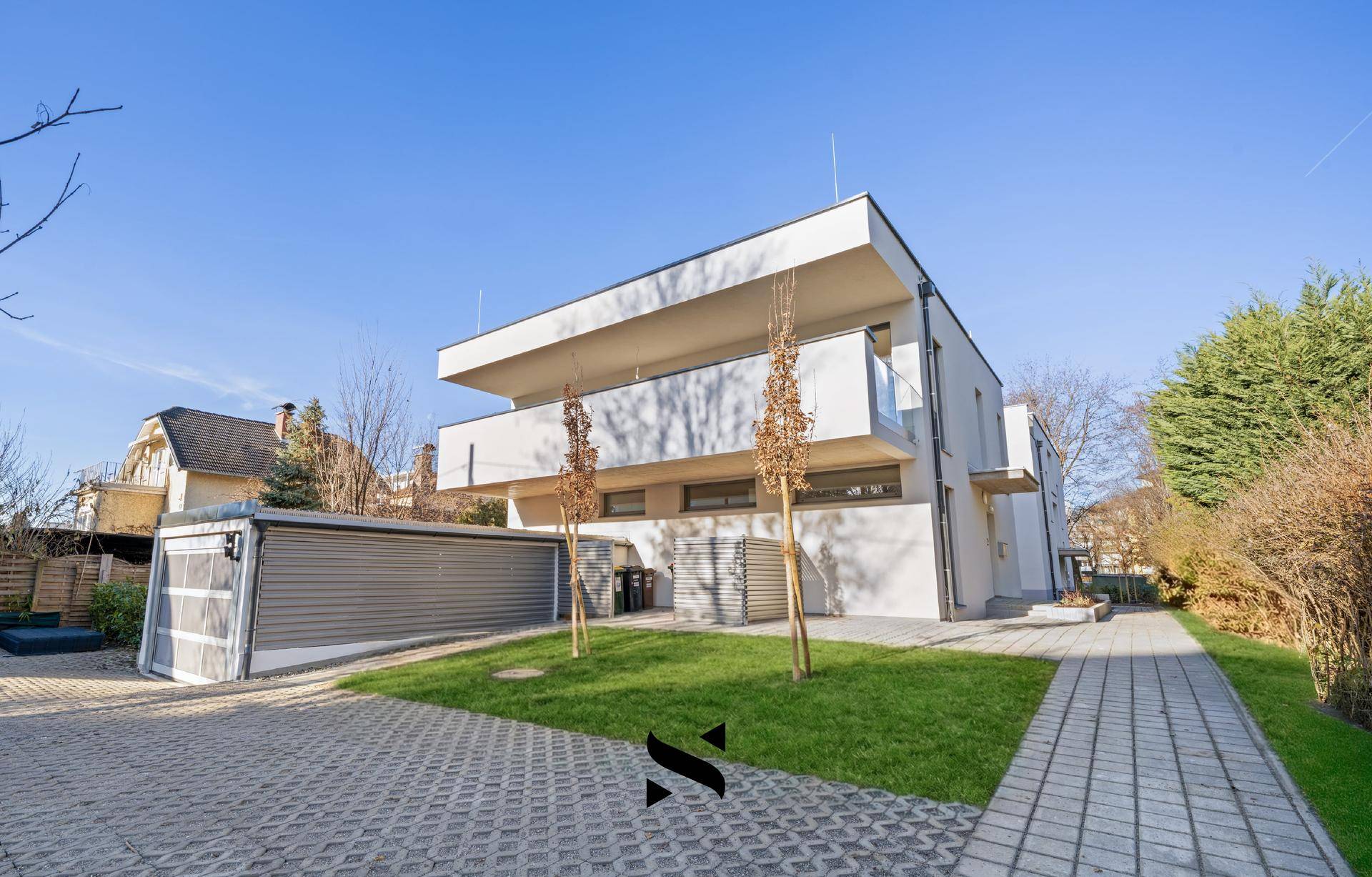 Modernes Mehrfamilienhaus mit klarer Architektur, Grünflächen und Parkmöglichkeiten.