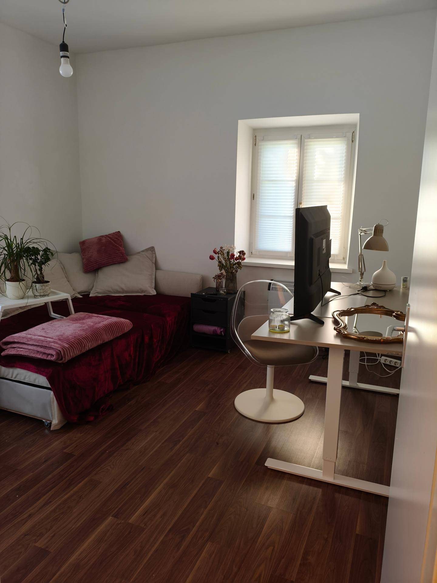 Helles Zimmer mit Schlafsofa, Schreibtisch und Fenster, ideal als Schlaf- oder Arbeitsbereich.