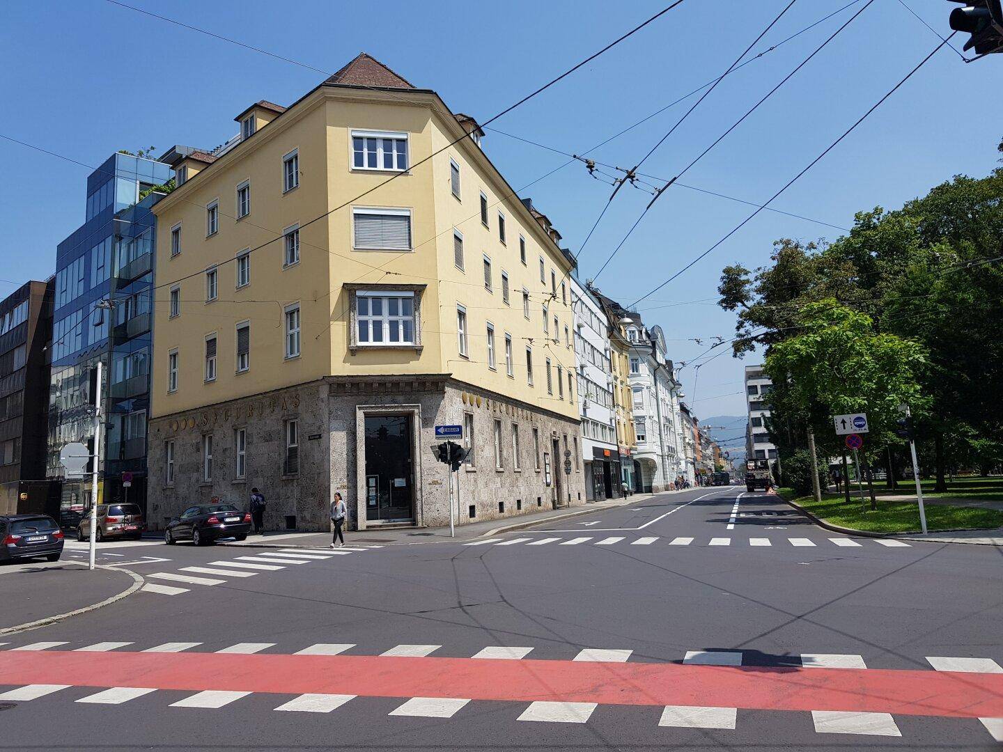 Eine belebte Straßenecke mit einem charmanten gelben Gebäude und weiteren Häusern entlang der Straße.