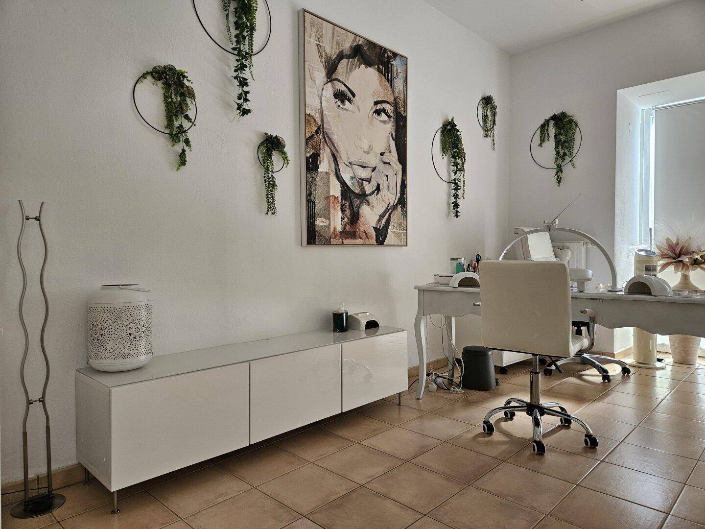 Geräumiger Behandlungsraum mit Kunst an der Wand, modernen Möbeln und beigen Fliesenboden.