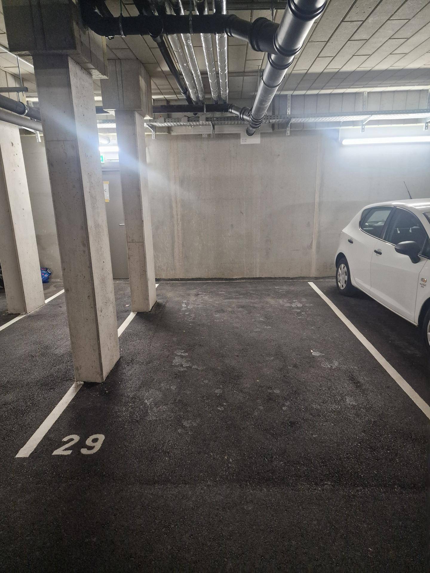 Tiefgaragenstellplatz Nummer 29 in einer modernen Tiefgarage mit Betonpfeilern und sichtbaren Leitungen.
