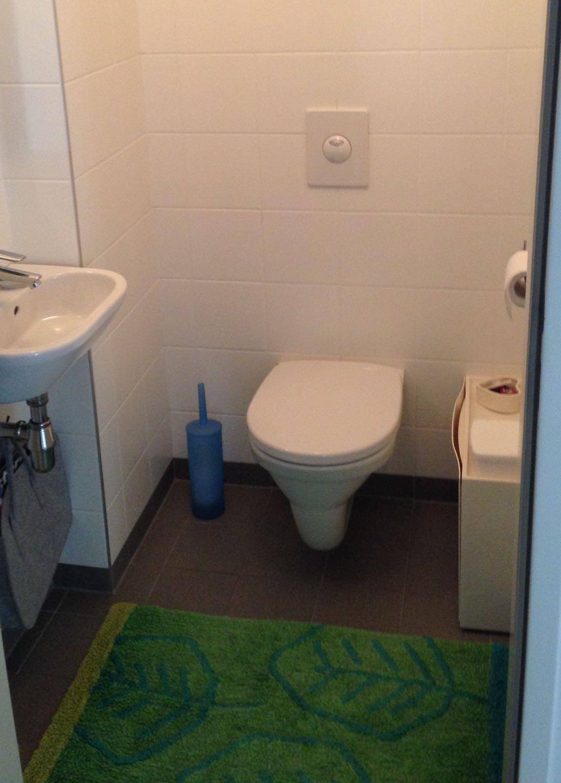 Modernes Gäste-WC mit wandhängender Toilette, Waschbecken und Fliesenboden.