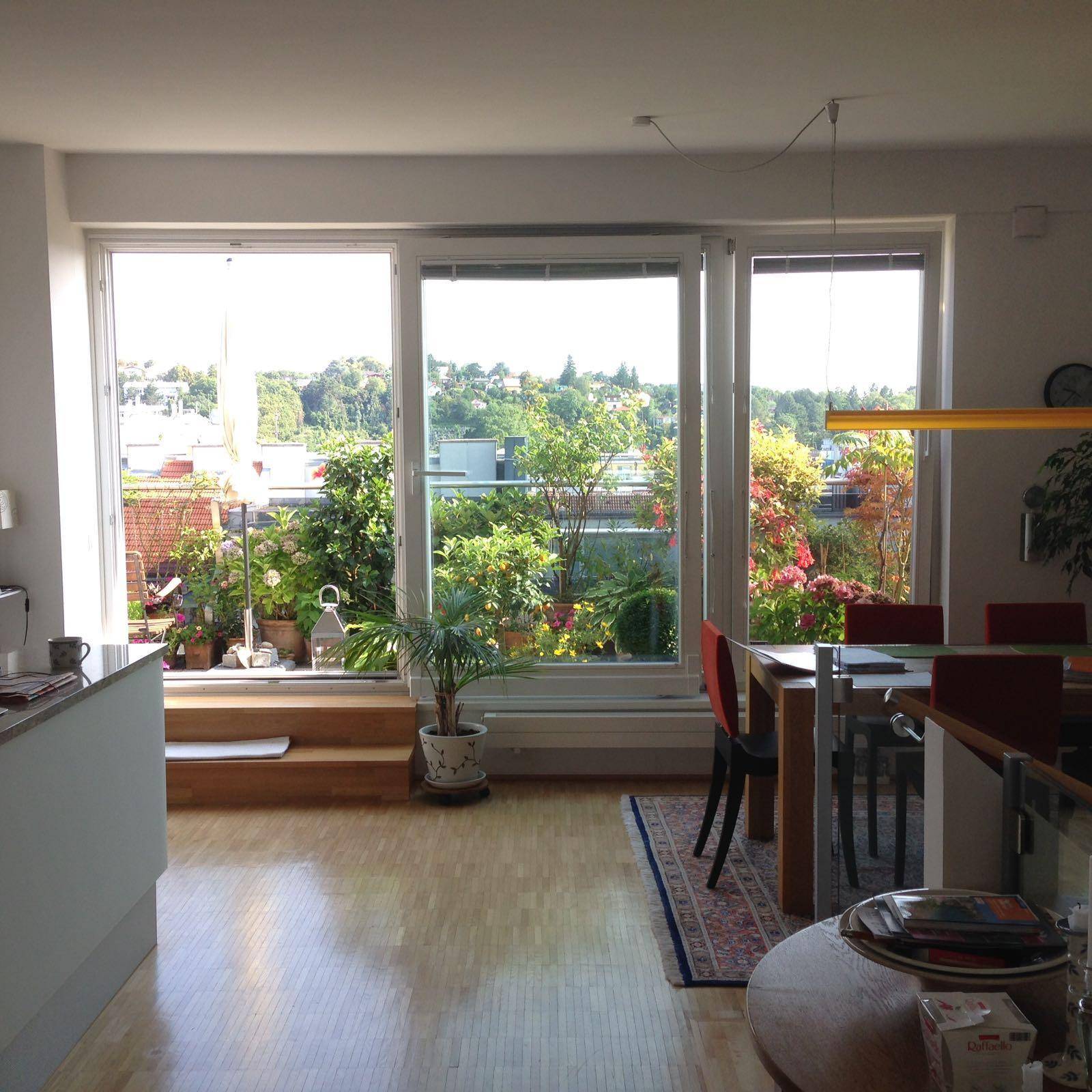 Heller Wohn- und Essbereich mit großen Fenstern und direktem Zugang zur begrünten Terrasse.