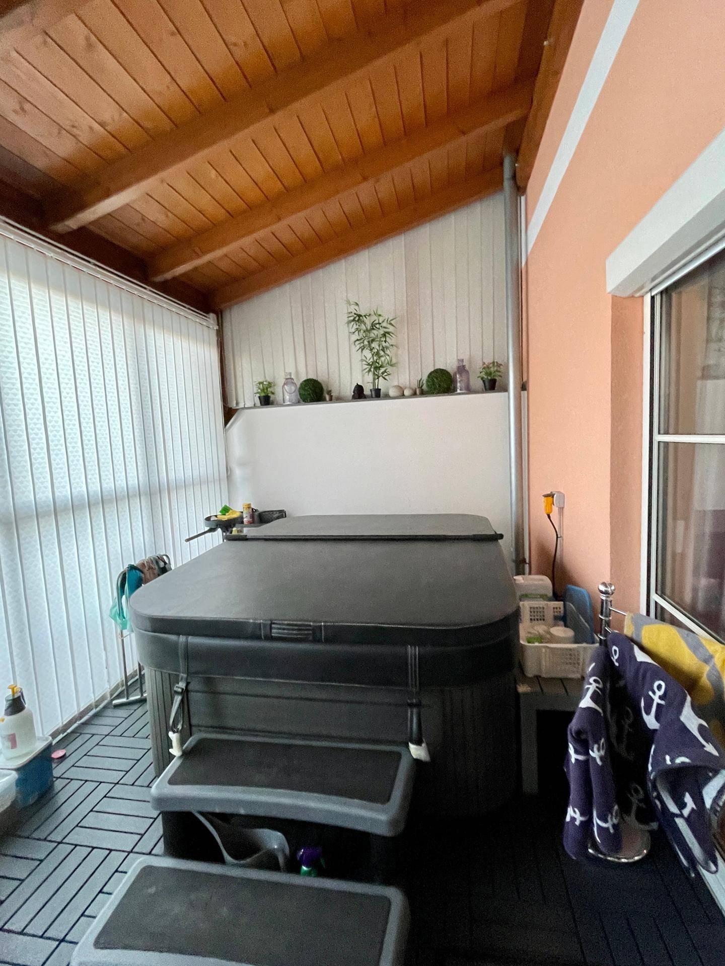 Entspannungsbereich im Wintergarten mit einem Whirlpool und Holzdecke, ideal zum Erholen.