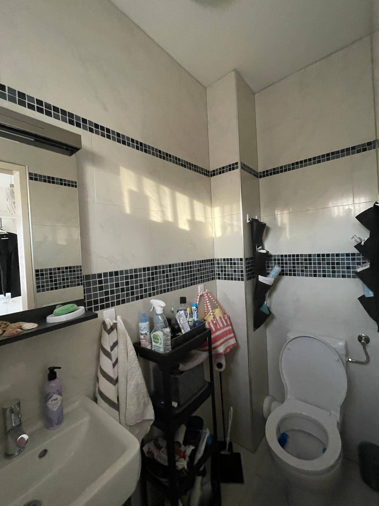Kleines Gäste-WC mit modernen Fliesen und einem Waschbecken, funktional eingerichtet.