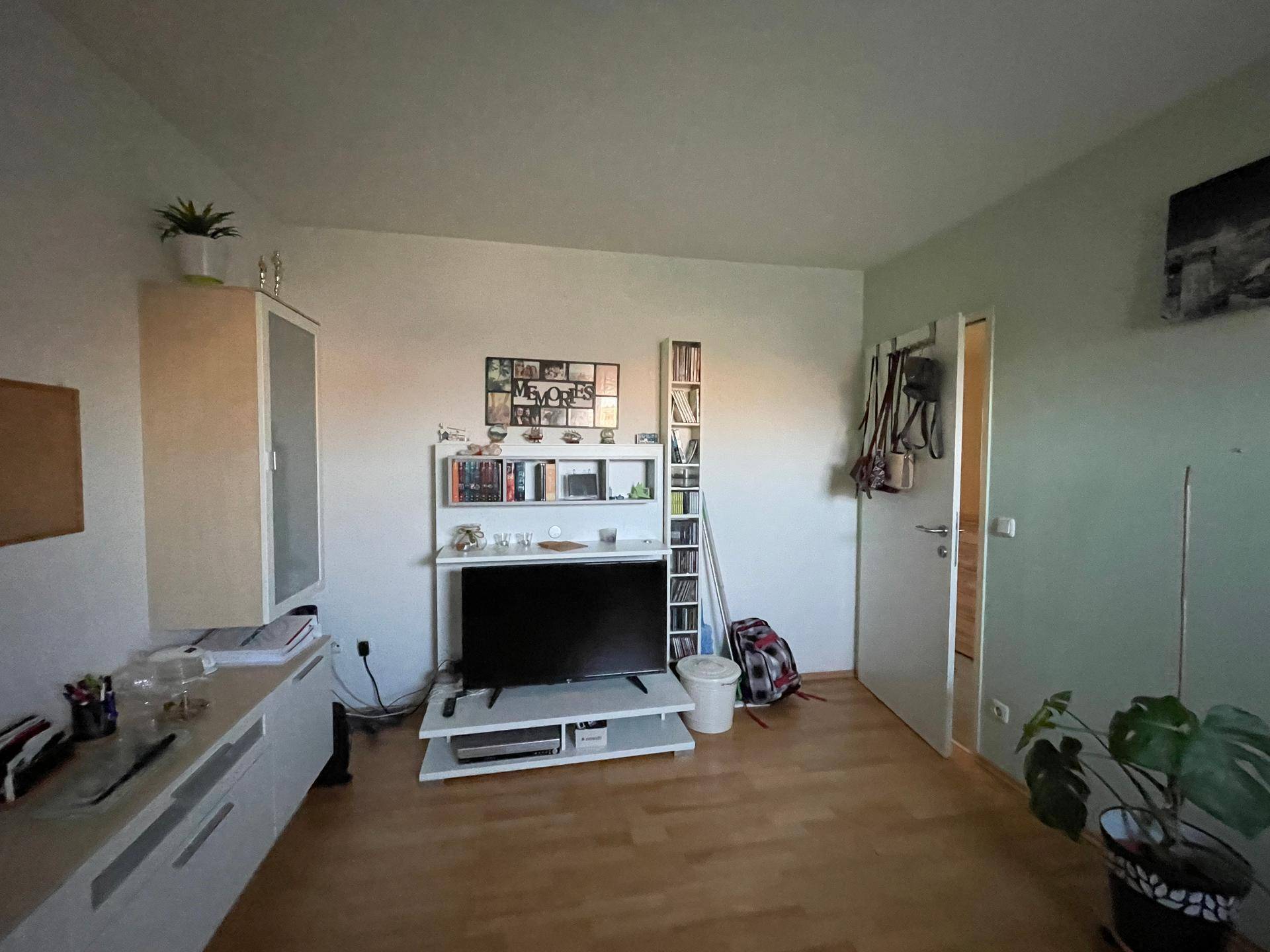 Helles Zimmer mit Holzfußboden, Schreibtisch und Regalen, vielseitig nutzbar.