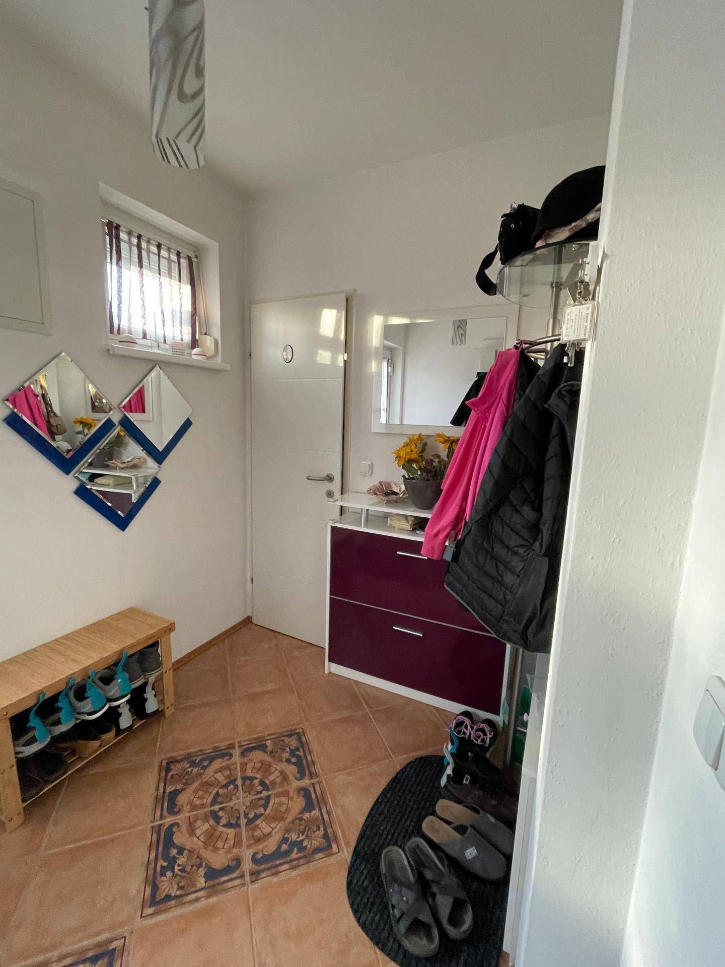 Heller Flur mit gemusterten Fliesen, Schuhregal und Garderobe, einladend gestaltet.