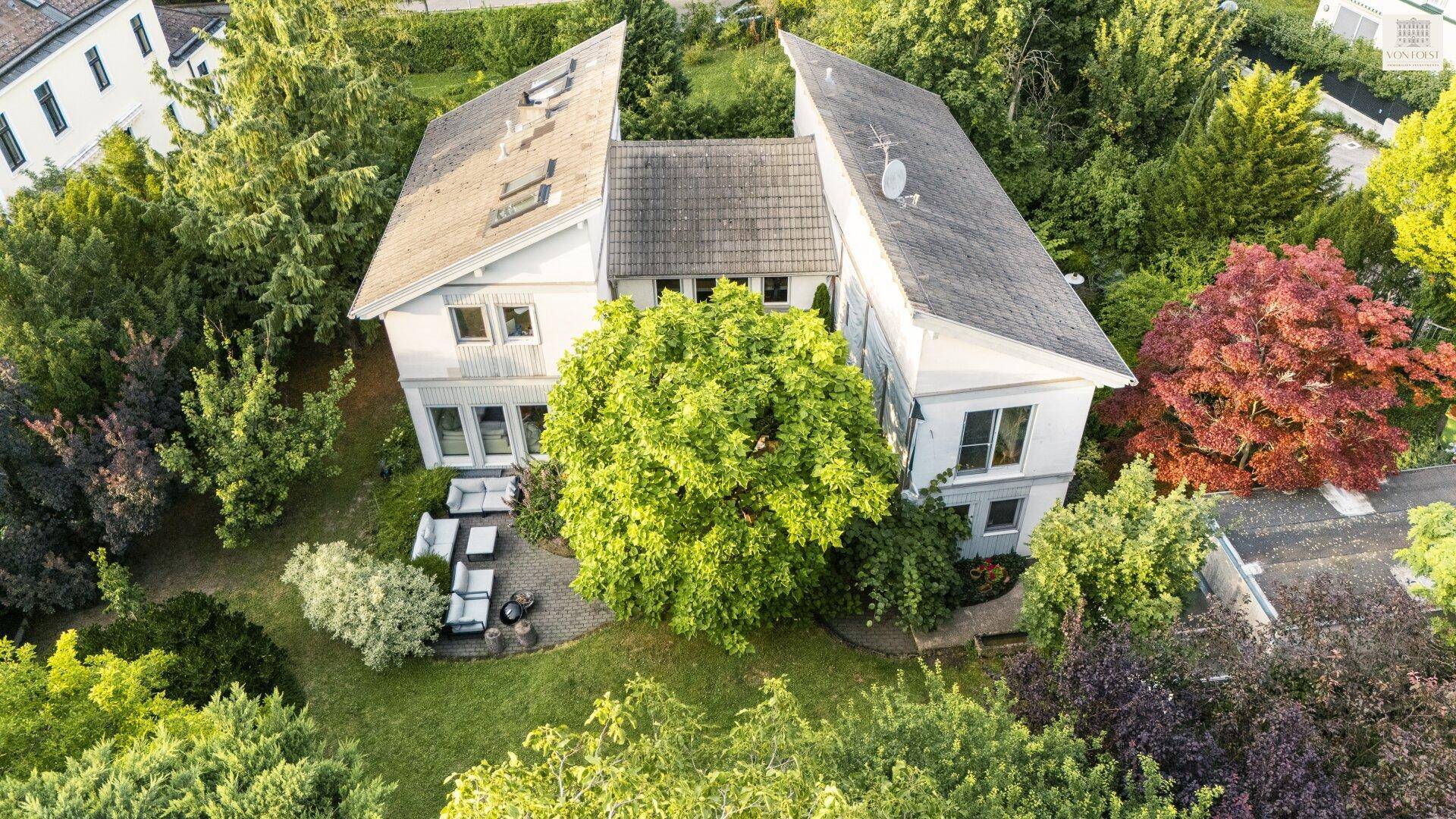 Luftaufnahme des Anwesens mit modernem Haus, großem Garten und umliegenden Bäumen.