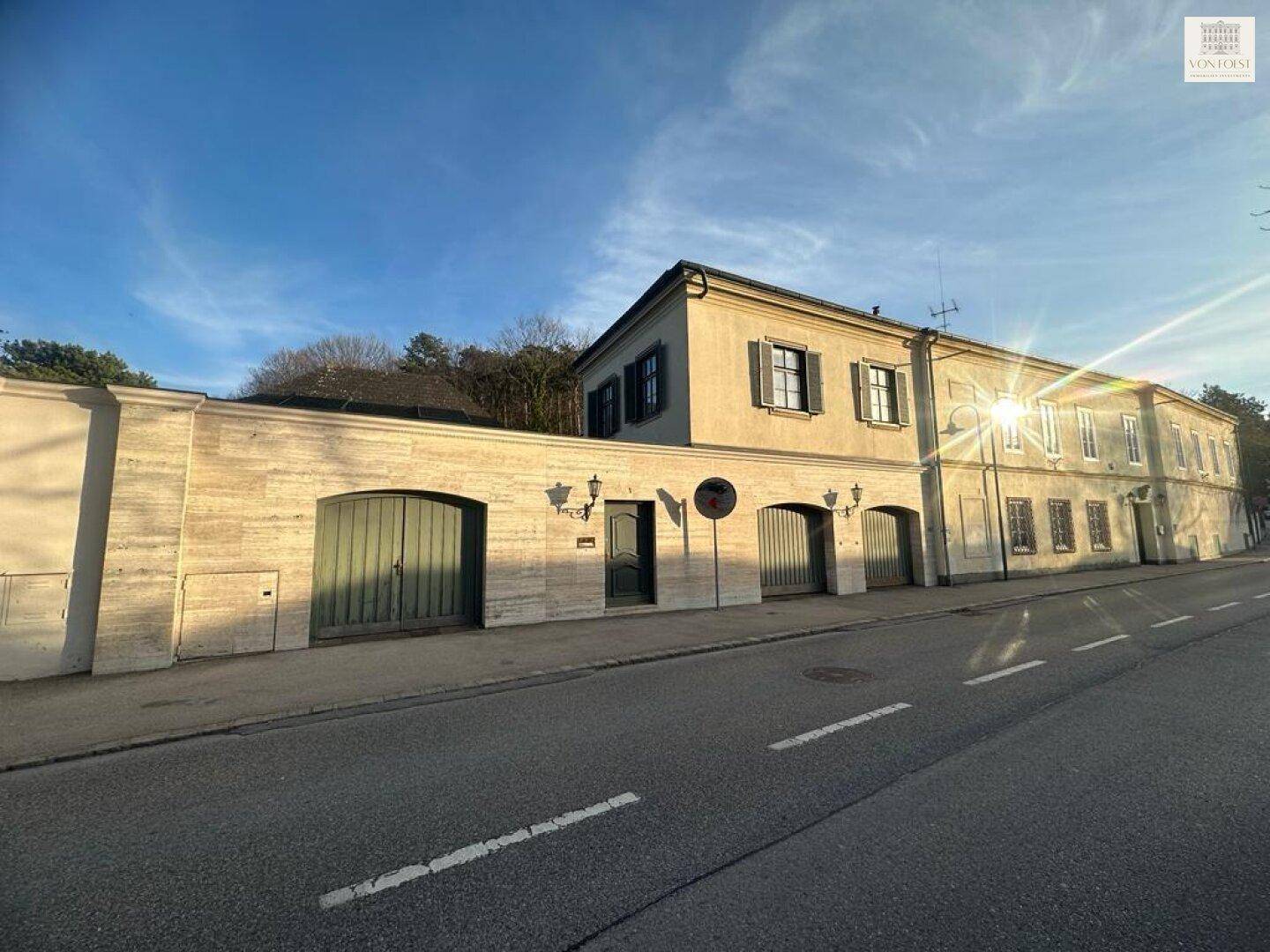Historisches Gebäude an der Straße bei Sonnenuntergang, mit markanter Fassade und Garagenzugängen.