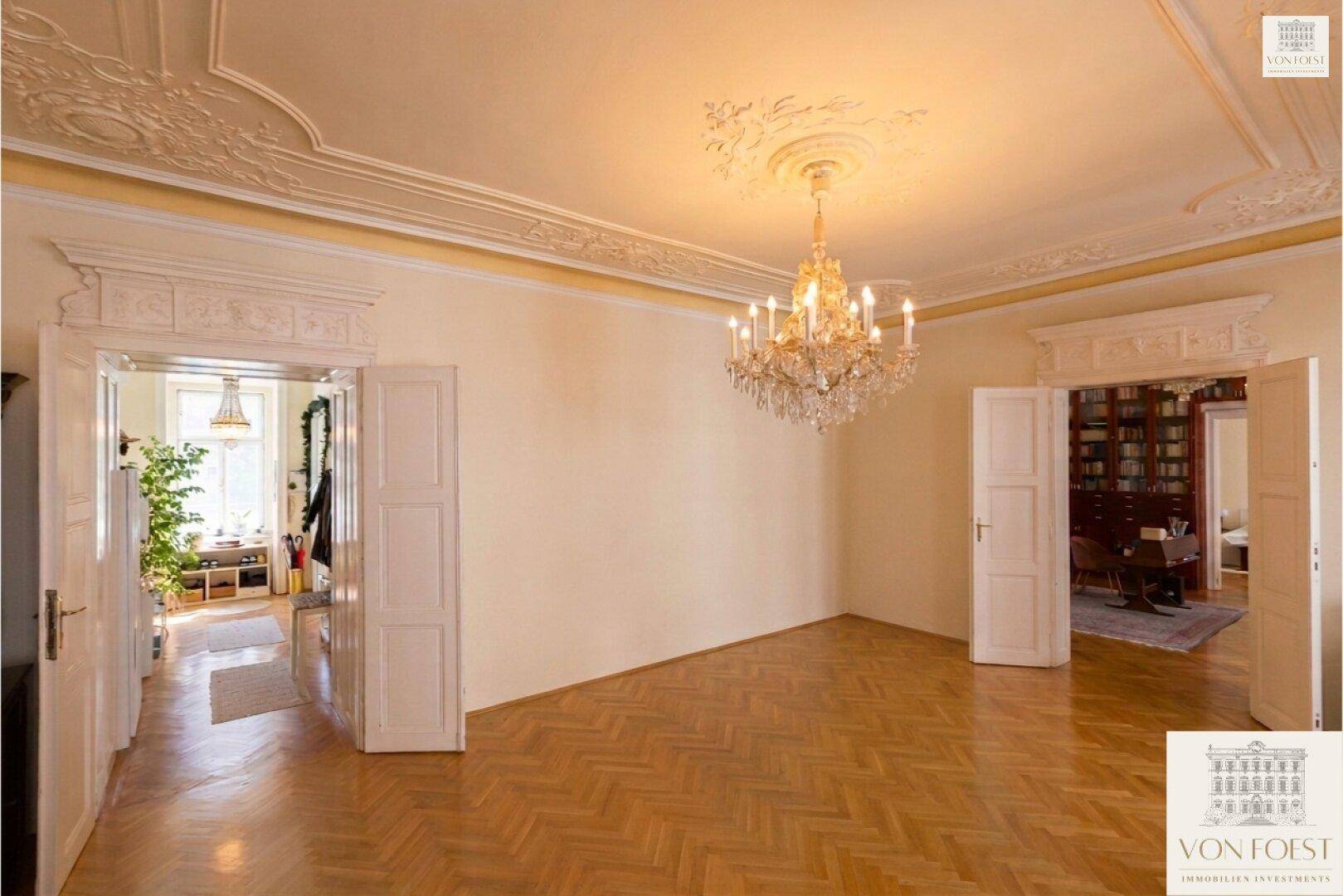 Elegantes Zimmer mit Fischgrätparkett, Stuckdecken und Blick in angrenzende Räume.