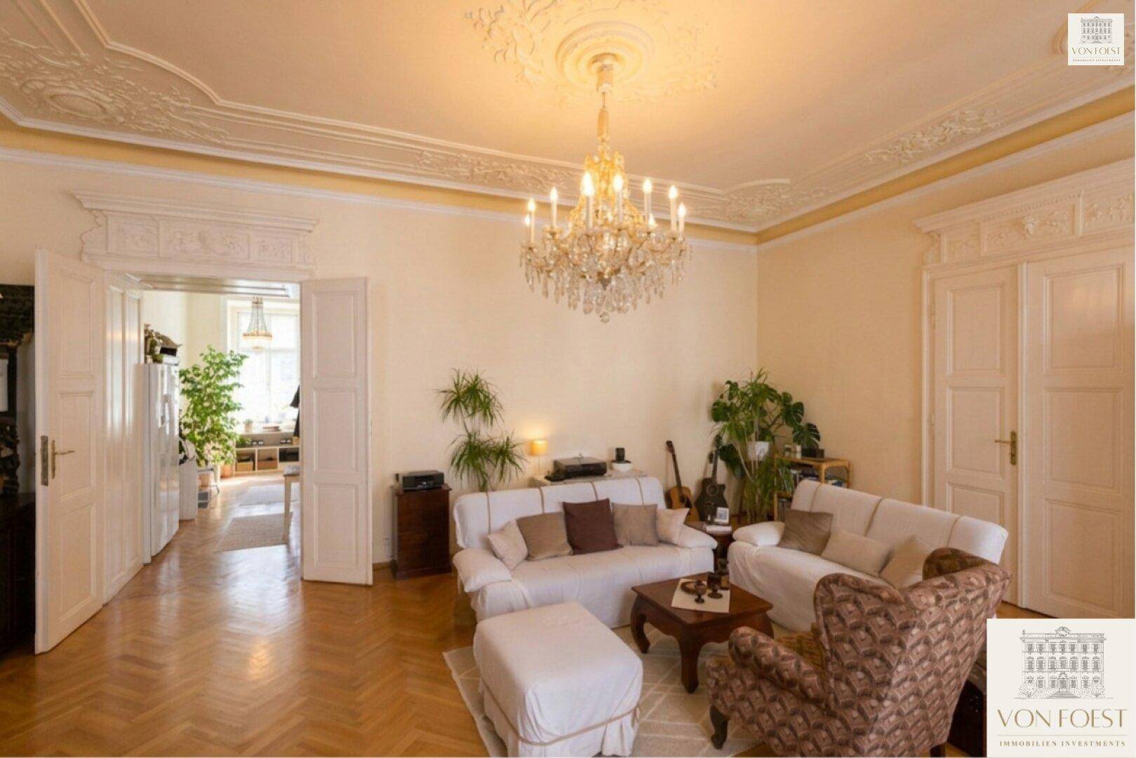 Gemütliches Wohnzimmer mit Sofas, Pflanzen und klassischem Fischgrätparkett.