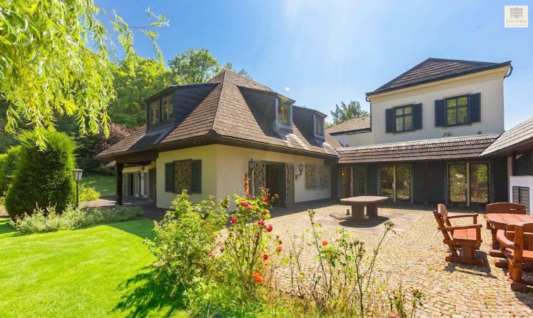Charmante gepflasterte Terrasse mit rustikalen Holzmöbeln und Blick auf die historische Hausfassade.