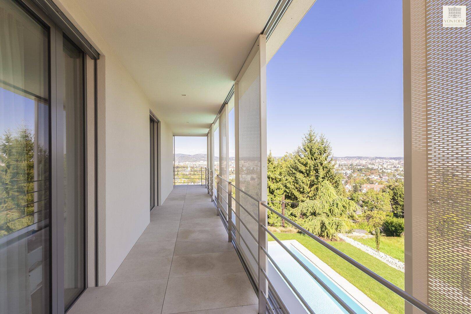 Lange Loggia mit Metallgeländer und weitem Blick über die Stadt und die umliegende Landschaft.