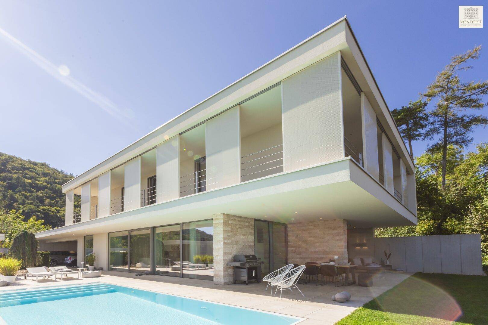 Elegantes modernes Wohnhaus mit weitläufigen Glasfronten, Pool und umgebender Natur.