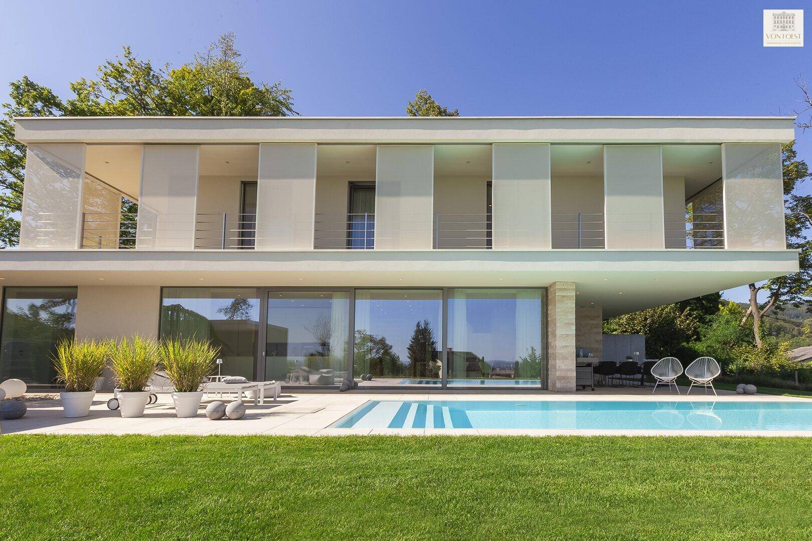 Moderne Villa mit klaren Linien, großen Fensterfronten und einem einladenden Poolbereich.