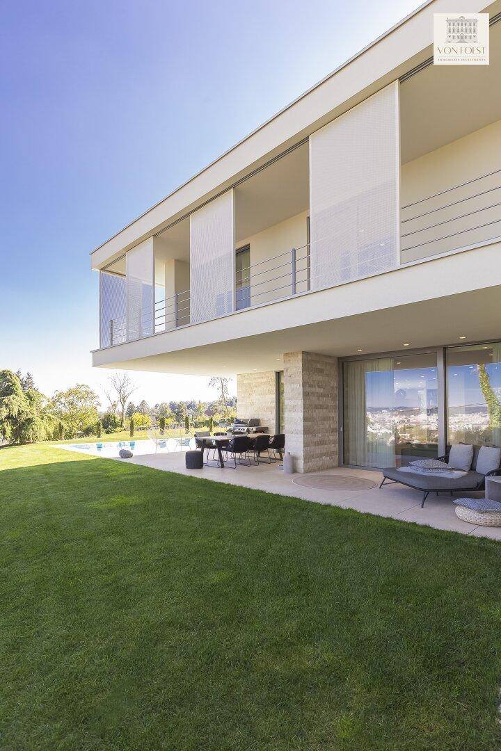 Weitläufiger Garten mit Rasenfläche, Terrasse und Pool, der einen Panoramablick auf die Umgebung bietet.