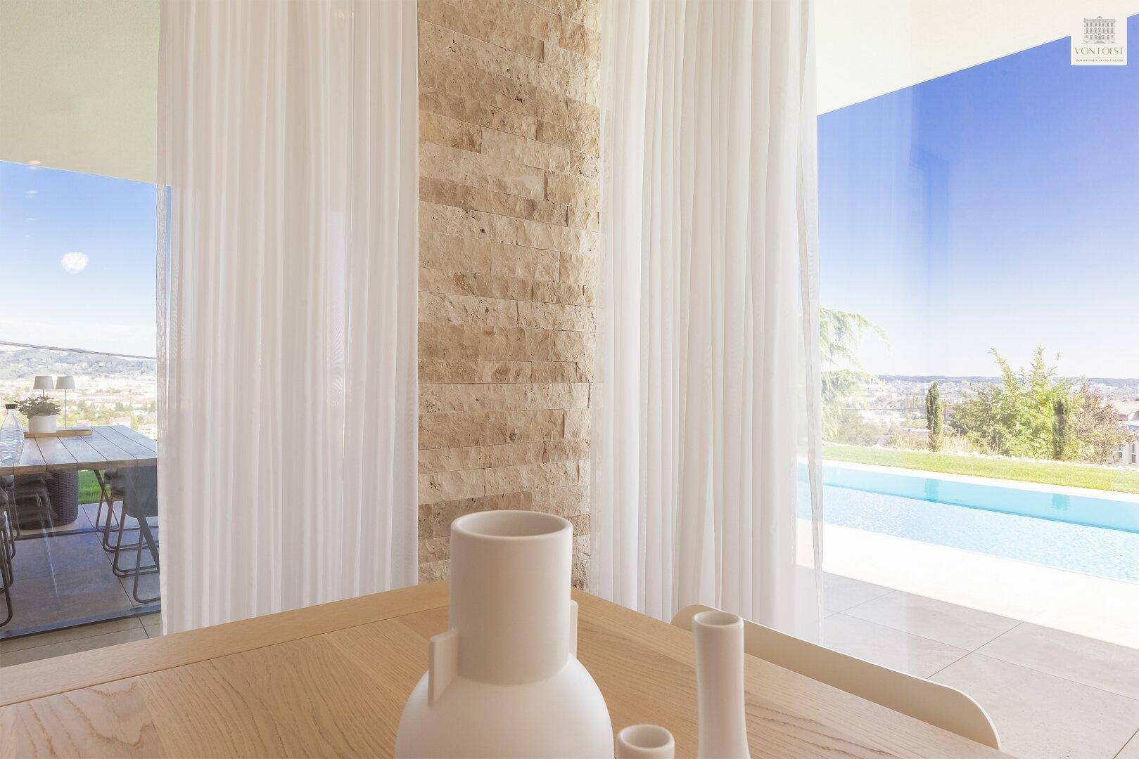 Detailansicht des Essbereichs mit Holztisch, weißen Vasen und Blick auf den Pool.