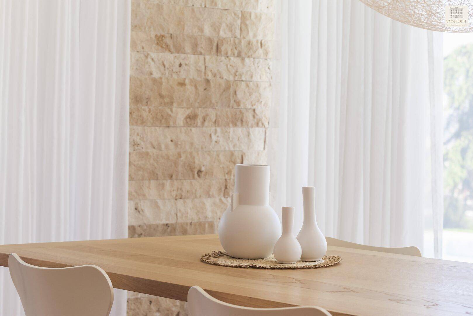 Nahaufnahme eines Holztisches mit minimalistischer Dekoration und Steinwand im Hintergrund.