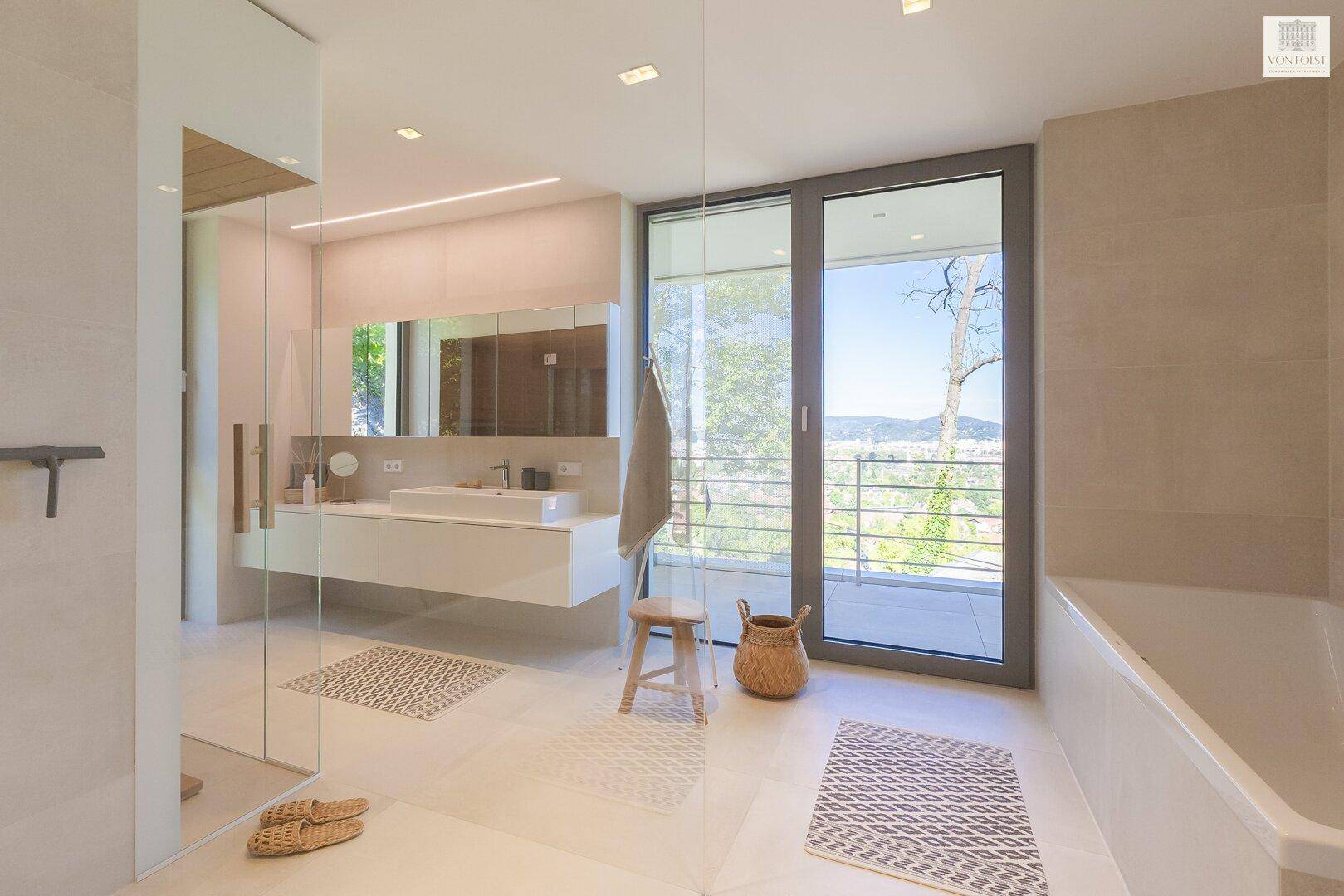 Geräumiges modernes Badezimmer mit Badewanne, Doppelwaschbecken und großen Fenstern.