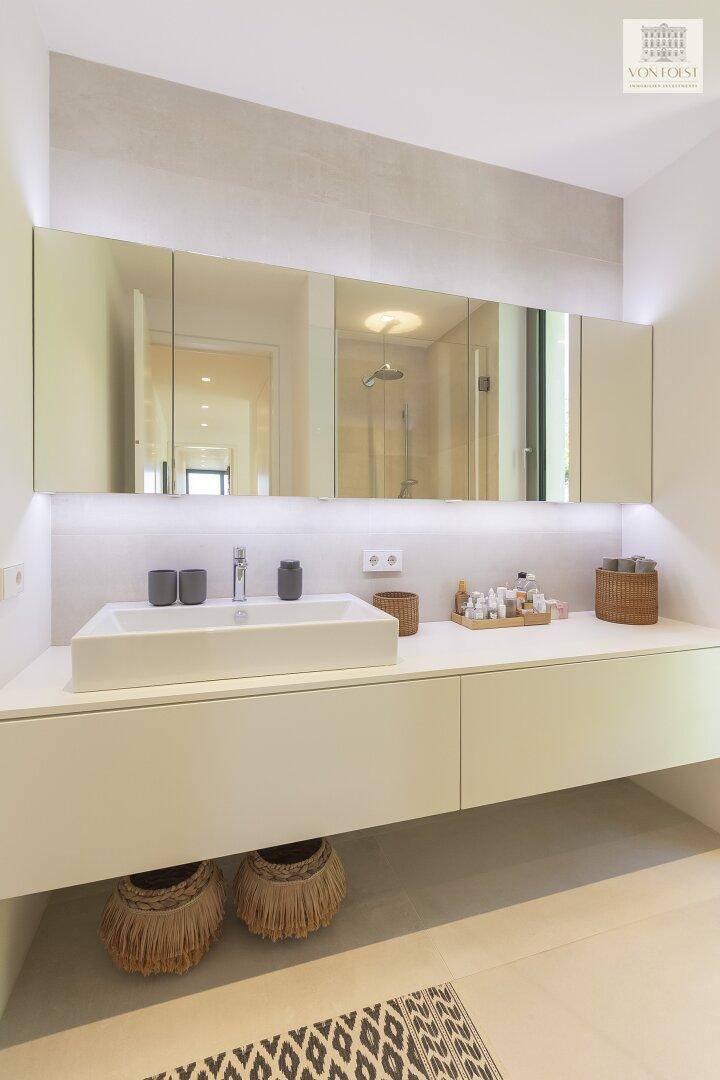Moderner Waschtisch mit Einzelwaschbecken, großem Spiegelschrank und indirekter Beleuchtung.