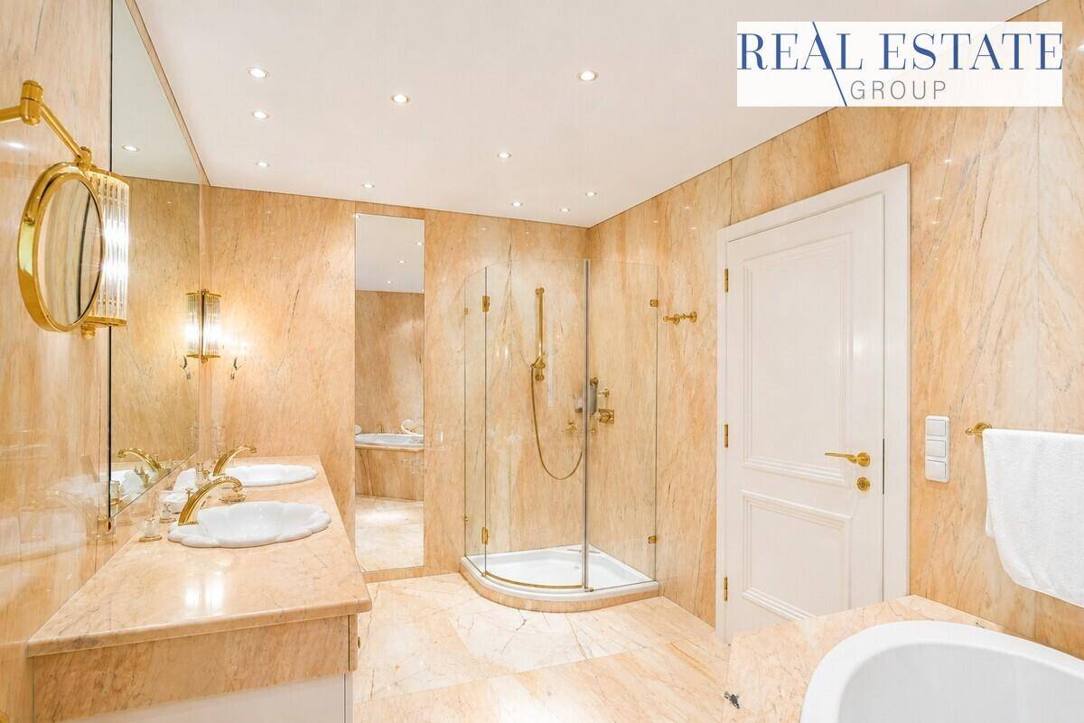 Luxuriöses Badezimmer mit doppelten Waschbecken, Dusche und Badewanne, komplett in Marmor gehalten.