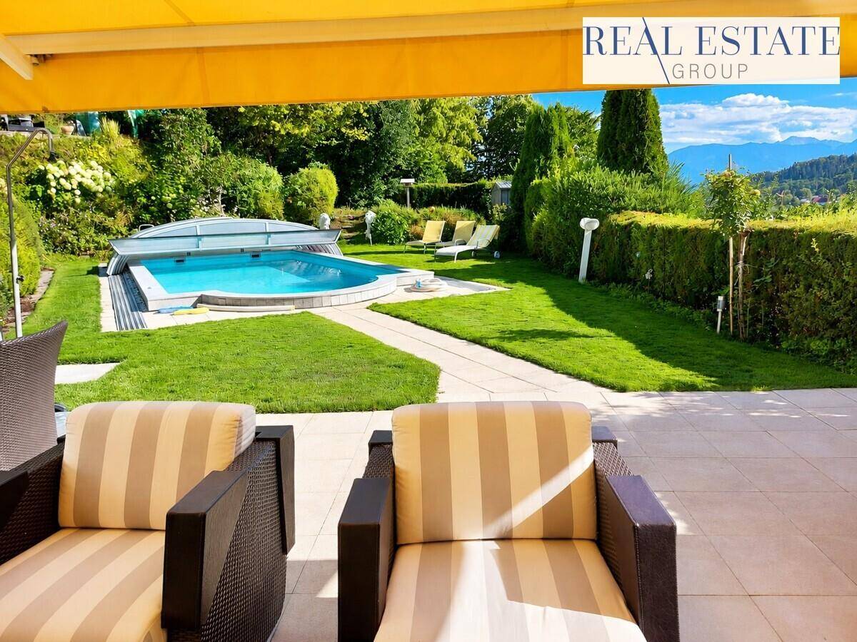 Gemütliche Terrasse mit Sitzgelegenheiten, Blick auf den Pool und die umliegende grüne Landschaft.