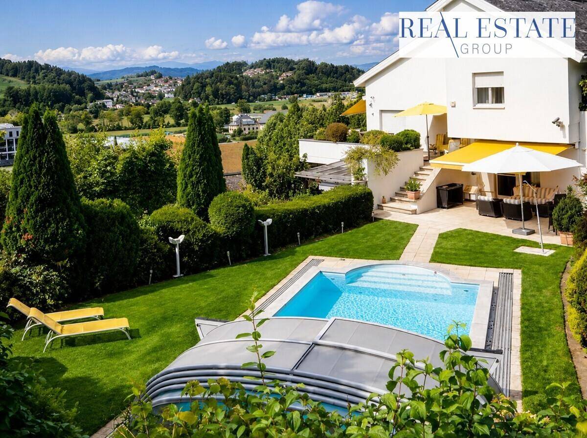 Gepflegter Gartenbereich mit Swimmingpool, Liegestühlen und weitem Blick auf die Landschaft.