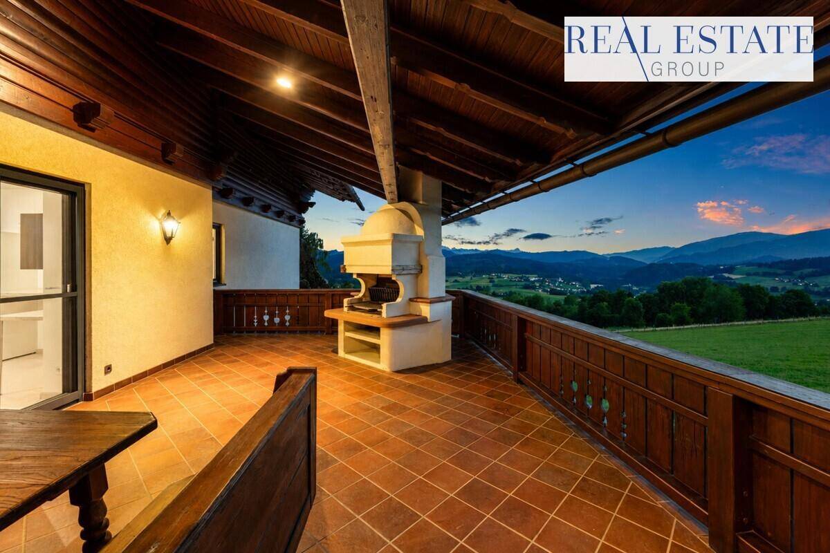 Überdachter Balkon mit traditionellem Holzgeländer, Fliesenboden und integriertem Grillbereich mit Bergblick.