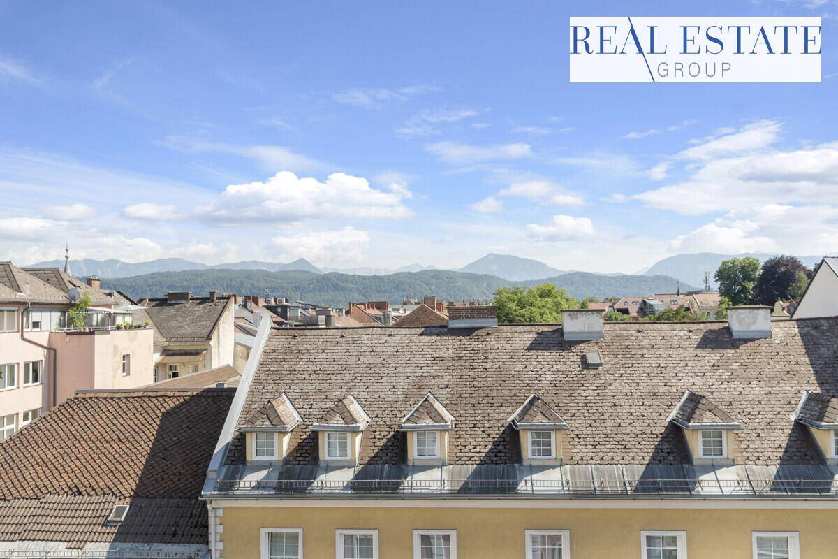 Panoramablick über die Dächer der Stadt mit majestätischen Bergen im Hintergrund.
