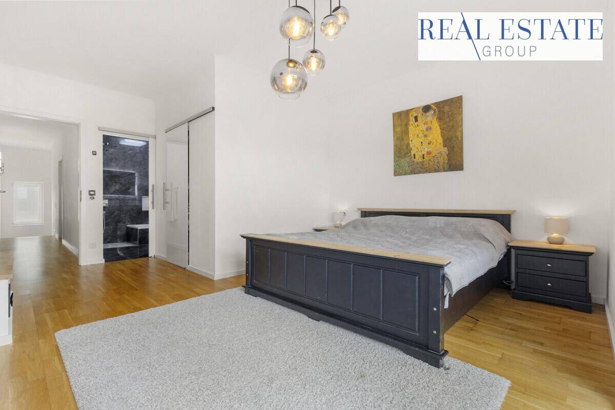 Schlafzimmer mit Holzboden, Doppelbett und Zugang zu einem modernen Badezimmer.