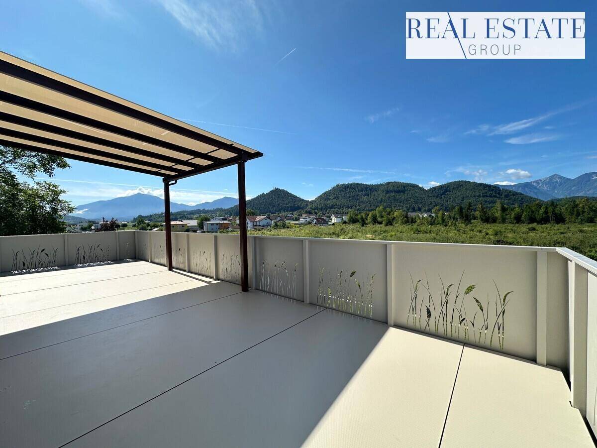 Weitläufige, sonnige Terrasse mit Pergola und Panoramablick auf die umliegende Bergwelt und Natur.