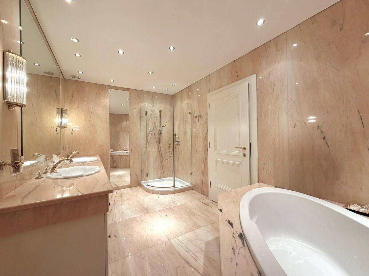 Luxuriöses Badezimmer mit rosafarbenem Marmor, Doppelwaschbecken, großer Dusche und freistehender Badewanne.