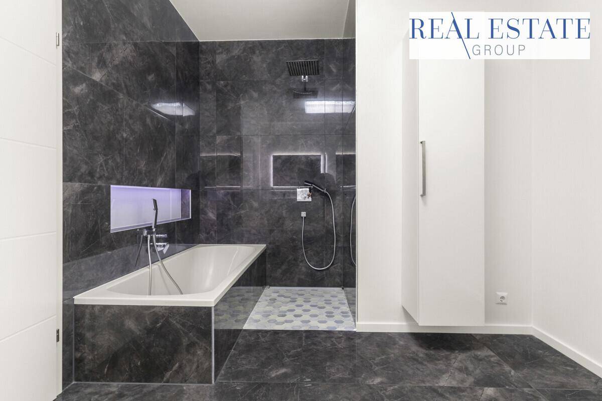 Modernes Badezimmer mit Badewanne, begehbarer Dusche und dunklen Fliesen.