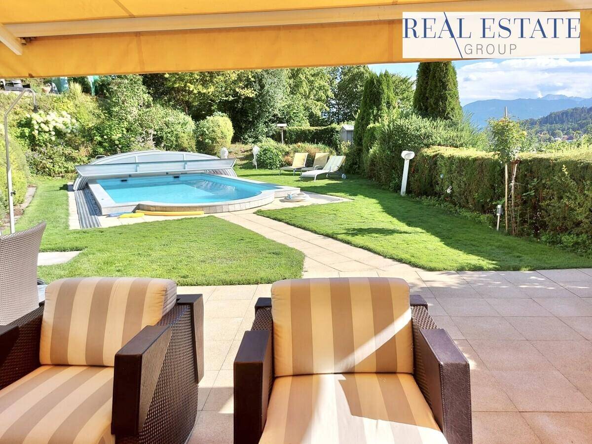 Geräumige Terrasse mit Sitzgelegenheiten, Blick auf den Pool, den Garten und die umliegenden Berge.