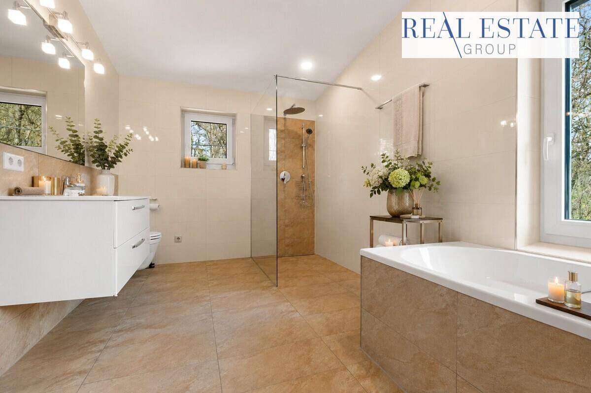 Großes, helles Badezimmer mit Badewanne, begehbarer Dusche und zwei Fenstern.