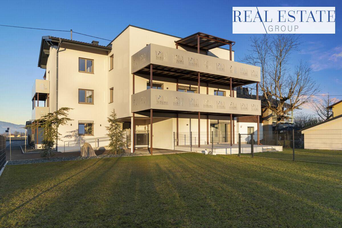 Modernes Mehrfamilienhaus mit Balkonen, Terrassen und gepflegter Rasenfläche im Vordergrund.