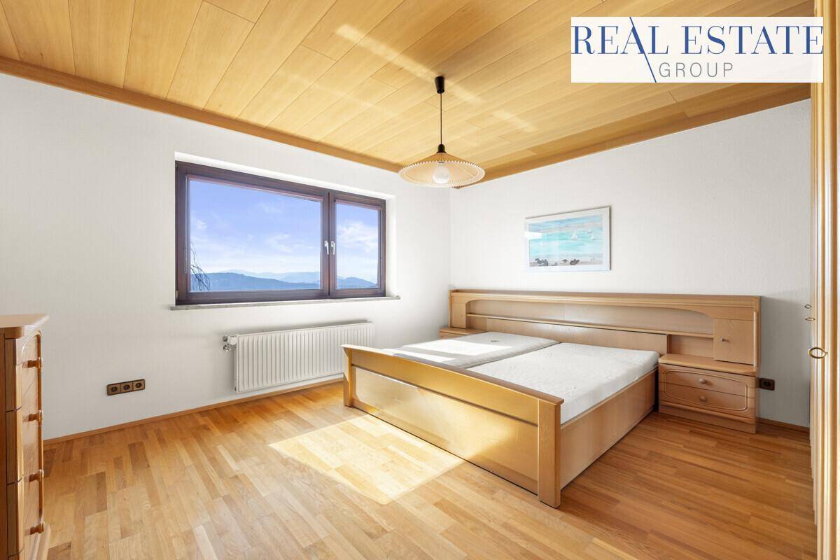 Gemütliches Schlafzimmer mit Holzboden, Holzdecke und großem Fenster mit Bergblick.