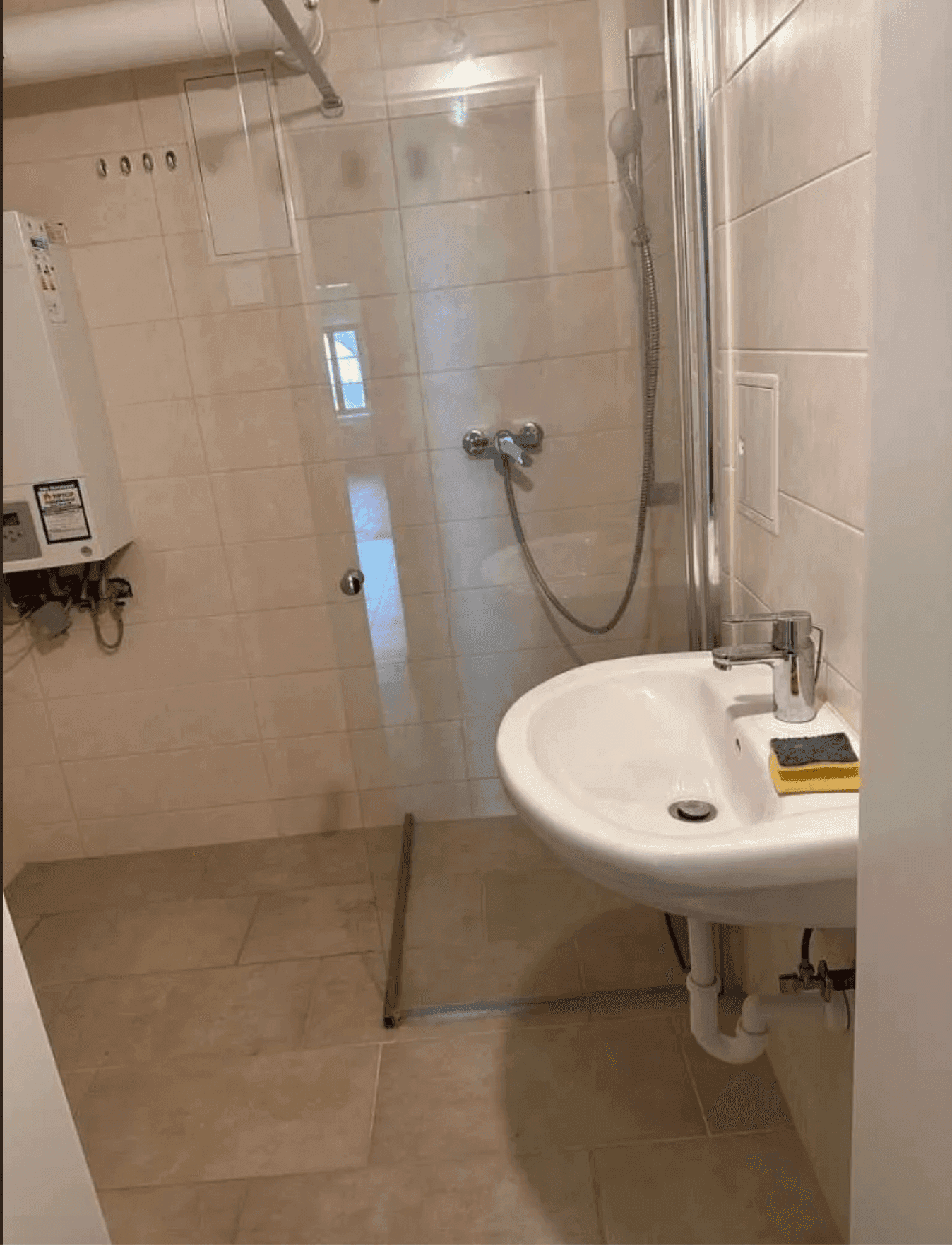 Modernes Badezimmer mit Dusche, Waschbecken und beigefarbenen Fliesen, hell und funktional.