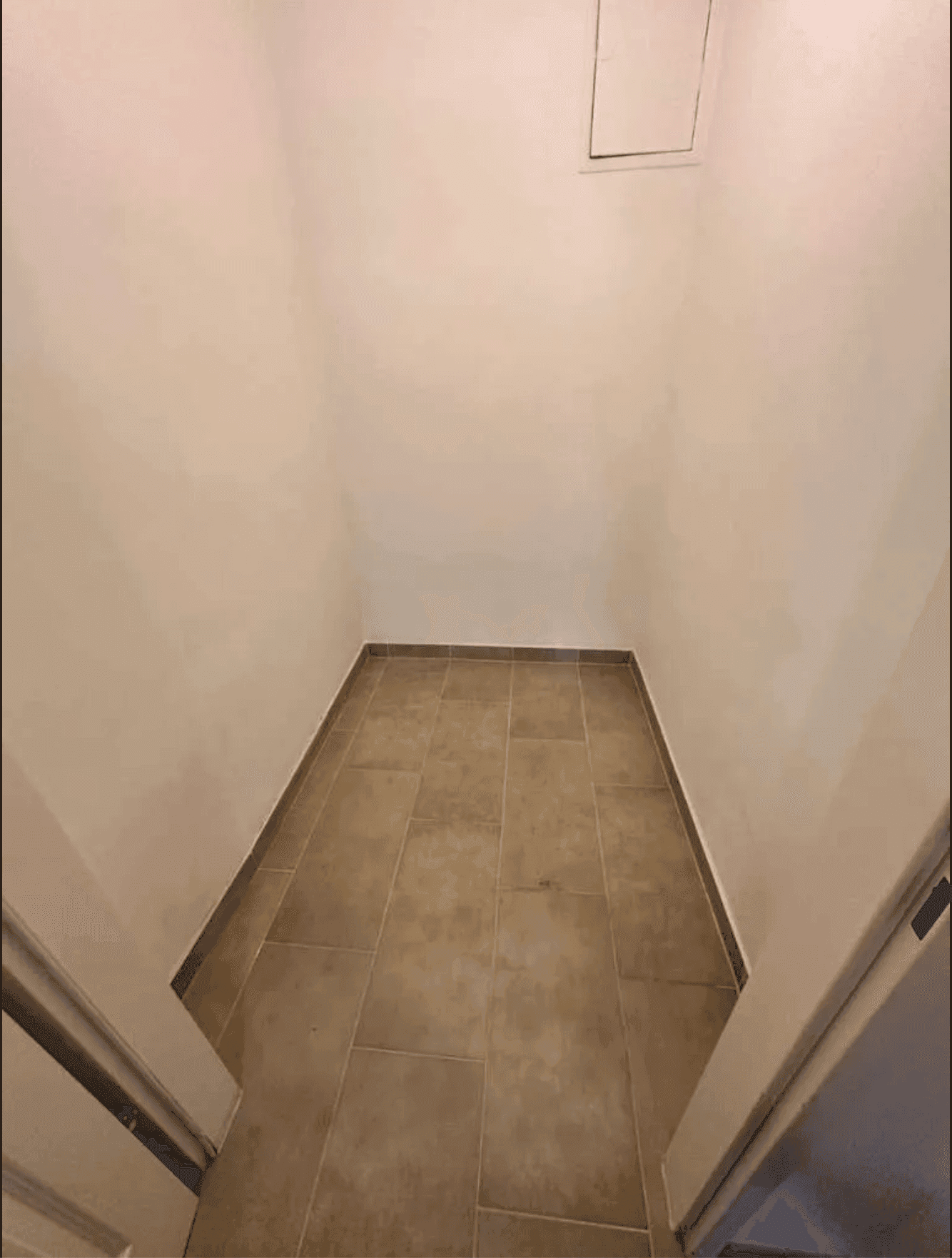 Kleiner Abstellraum mit Fliesenboden und einer Deckenluke, ideal für zusätzlichen Stauraum.