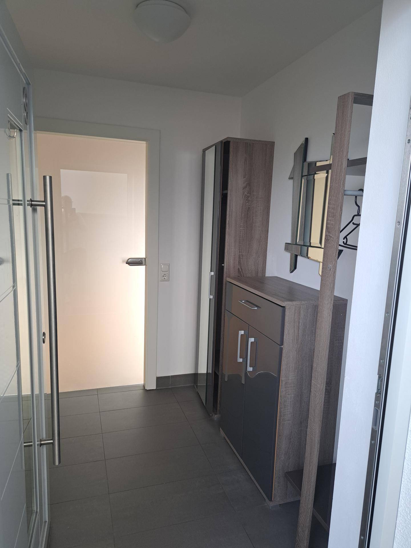 Eingangsbereich mit Fliesenboden und moderner Garderobe, führt zu weiteren Räumen.