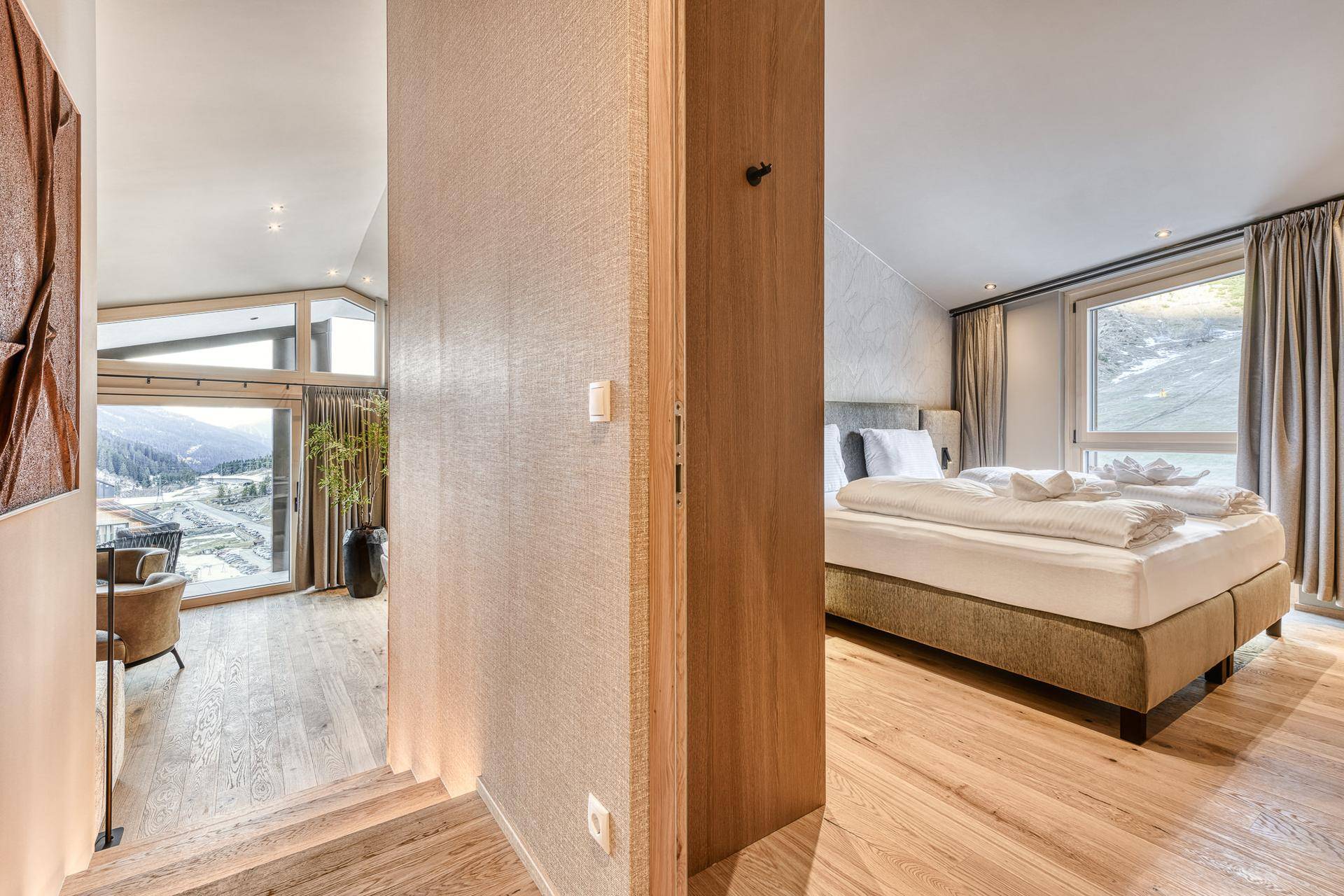 Heller Flurbereich mit Holztreppe und Zugang zu Schlafzimmer und Wohnbereich mit Bergblick.