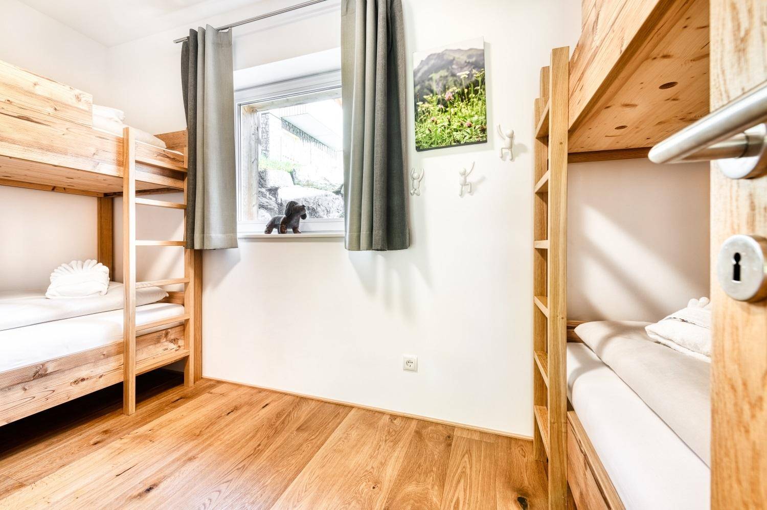 Schlafzimmer mit zwei Etagenbetten aus Holz und Blick ins Grüne.