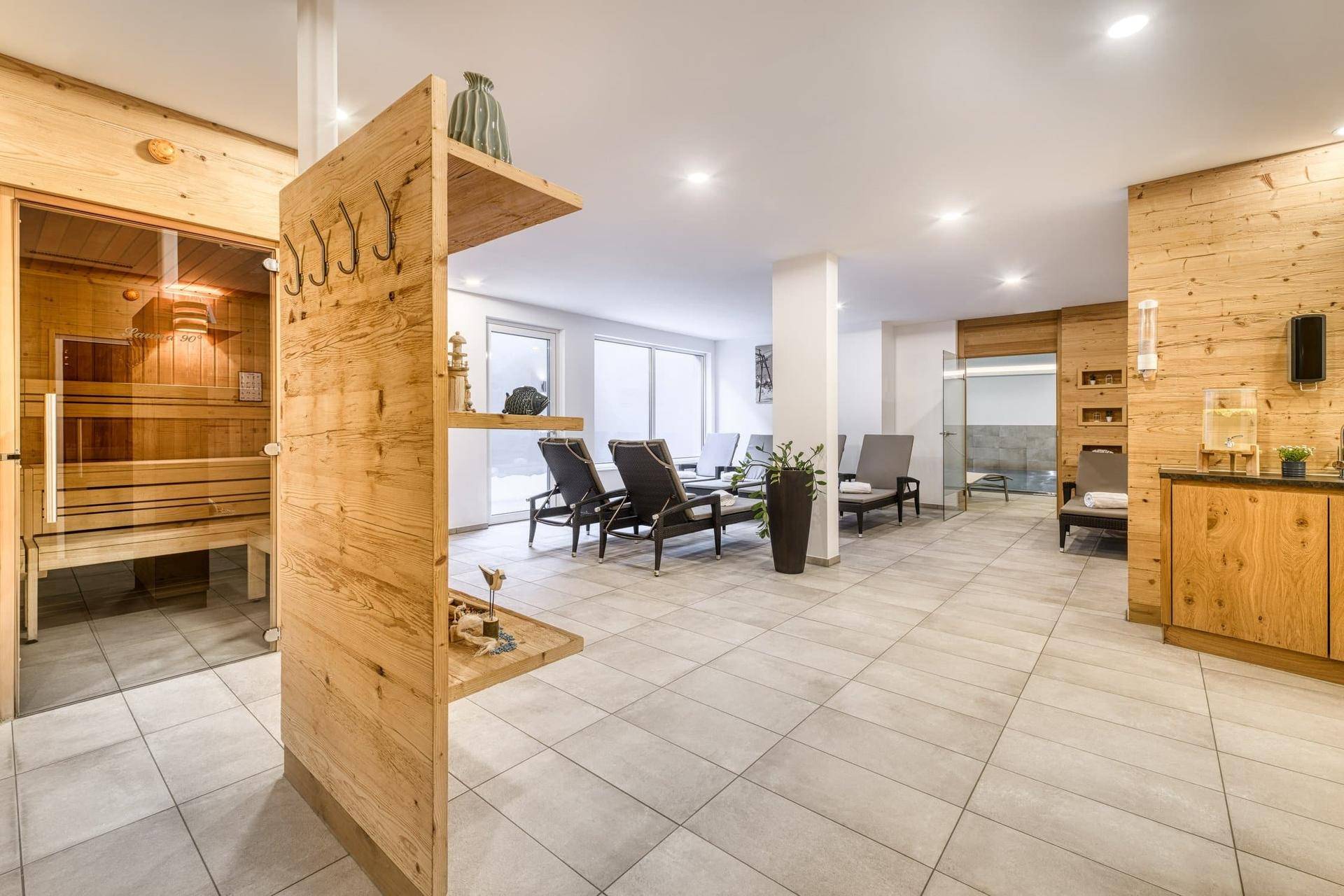 Heller und geräumiger Wellnessbereich mit Holzdetails, Entspannungsliegen und Sauna.
