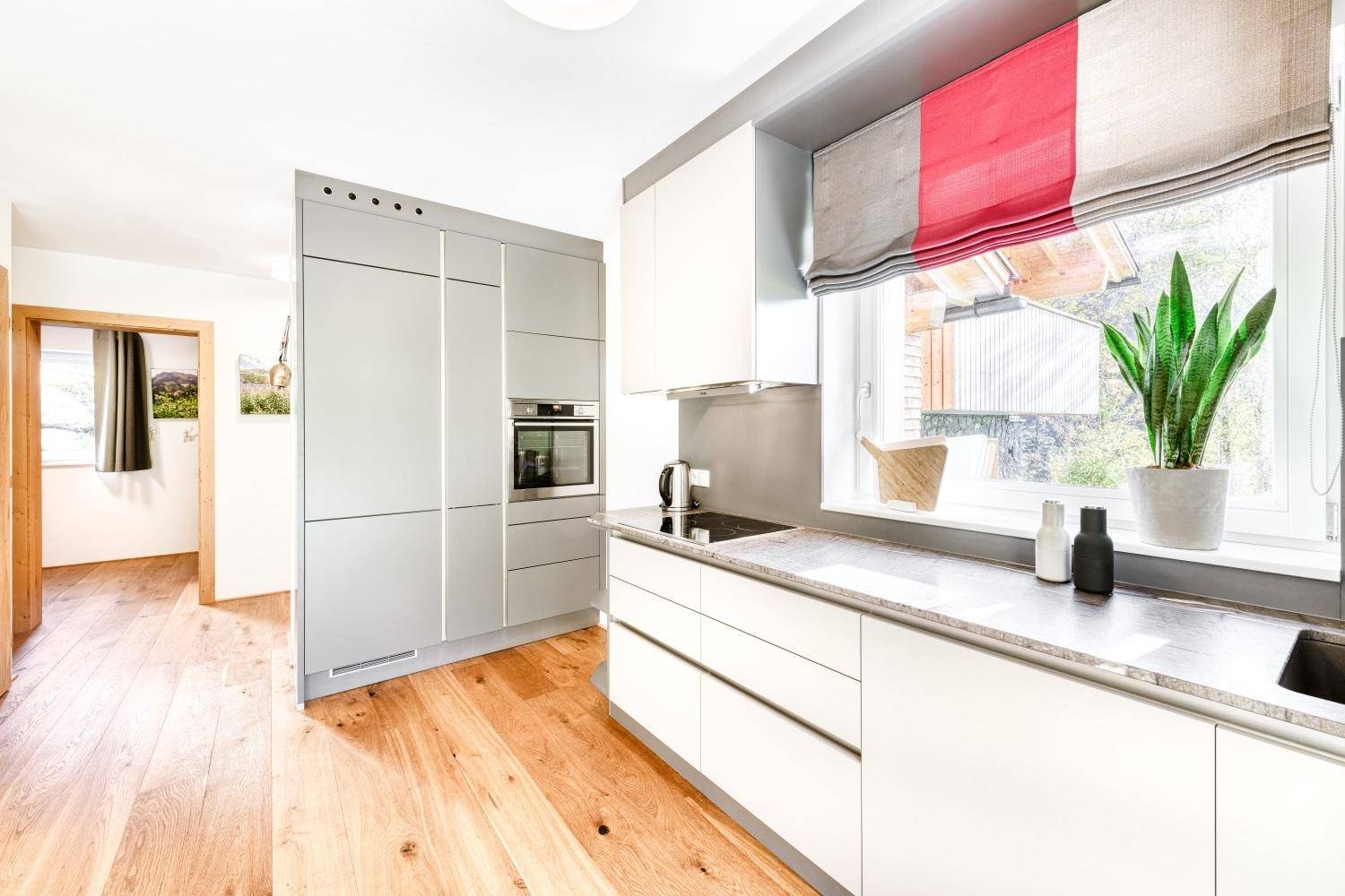 Moderne Küche mit weißen Schränken, integrierten Geräten und Holzboden.